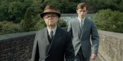 Actor Toby Jones (as Philip Burton) and Harry Lawtey (as Richard Jenkins), both wearing smart suits, in the BBC Films' feature film, Mr Burton.