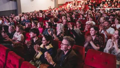 Sheffielf DocFest generic audience image showing cinema audience in red seats clapping after the house lights have come up.