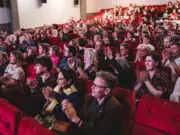 Sheffielf DocFest generic audience image showing cinema audience in red seats clapping after the house lights have come up.