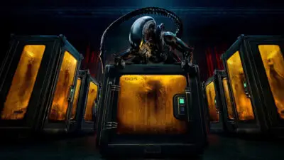 An alien creature - the familiar xenomorph known to fans of Ridley Scott's 1979 sci-fi horror Alien and later James Cameron's Aliens - sits on top of pods containing other malevolent alien creatures in a dark, low-lit image from the TV series, Alien: Earth.